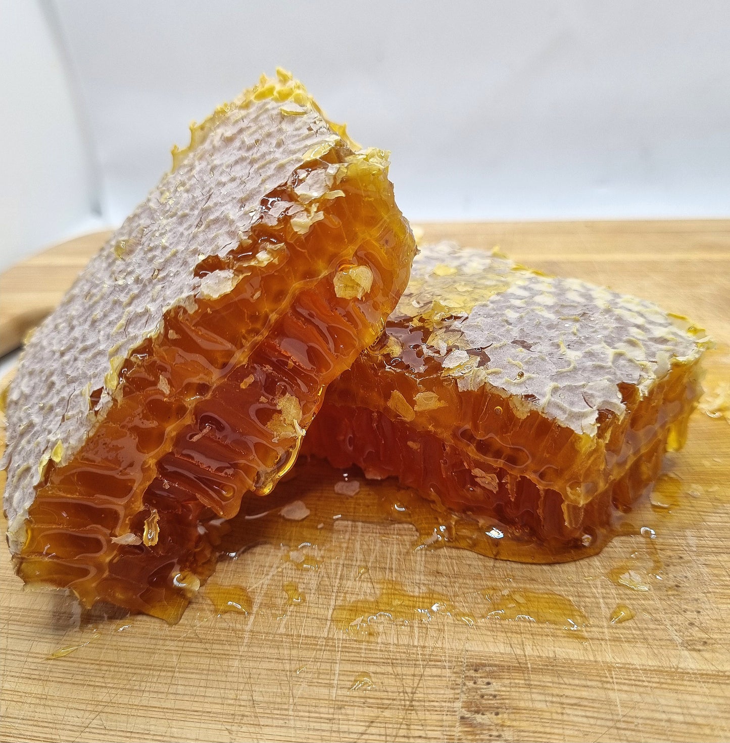 Raw organic honeycomb cut into pieces on a wooden board