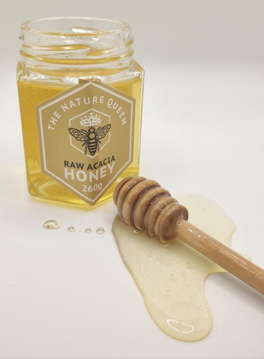 Raw acacia honey on wooden spoon